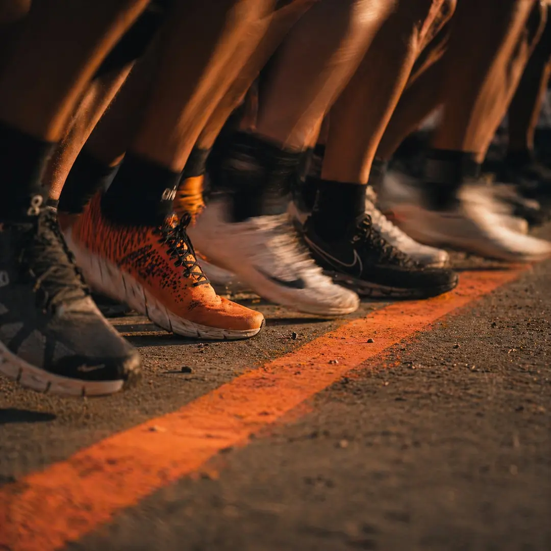Pieds d'athlètes au départ d'une course HYROX, ligne orange